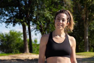 Genç kadın spor yaptıktan sonra dinleniyor ve kameraya gülümsüyor. Sağlıklı bir yaşam tarzı. Seçici odak.