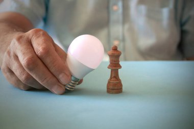 Elektrik işi konsepti. Ampul ve satranç taşı. Uzayı kopyala Seçici odak.