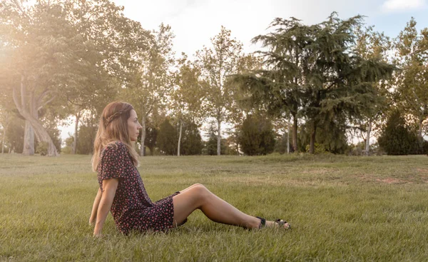 Jonge Vrouw Zittend Het Gazon Van Een Park Kijkend Naar — Stockfoto