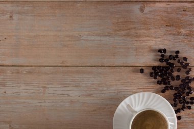 Kahve fincanı ve tahtanın üzerinde kahve çekirdekleri. Uzayı kopyala Seçici odak.