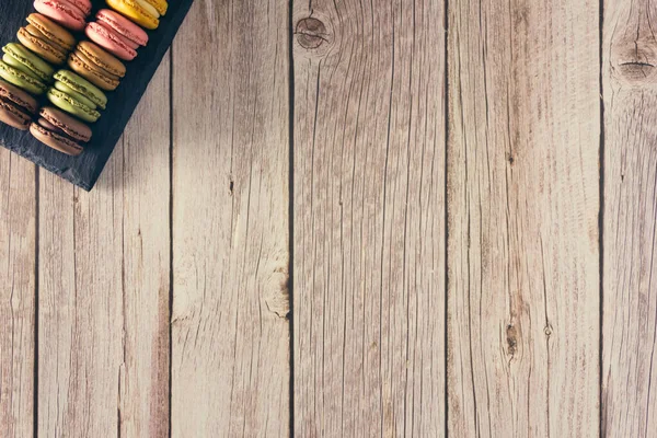 Pastel renkli Fransız kurabiyeleri, tahta tepside. Uzayı kopyala Seçici odak.