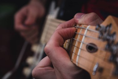Elektro gitarın tellerini koparan bir adam. Seçici odaklanma. Boşluğu kopyala.