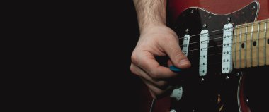 Elektro gitarın tellerini kazmayla koparan biri. Seçici odaklanma. Boşluğu kopyala.