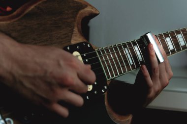 Elektro gitarın telleri boyunca boynunu kaydıran bir adam. Seçici odaklanma. Boşluğu kopyala.