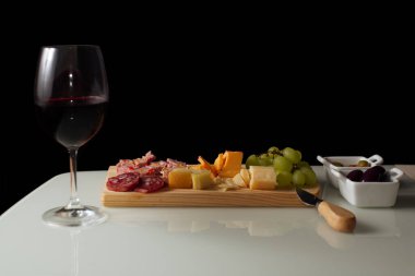 Kırmızı şarap, peynir ve atıştırmalık bir masa.