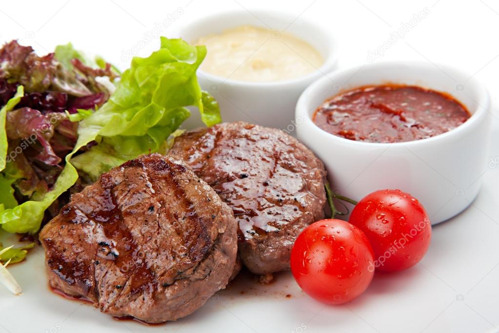 Barbecue grilled beef steak meat with vegetables and sauses.