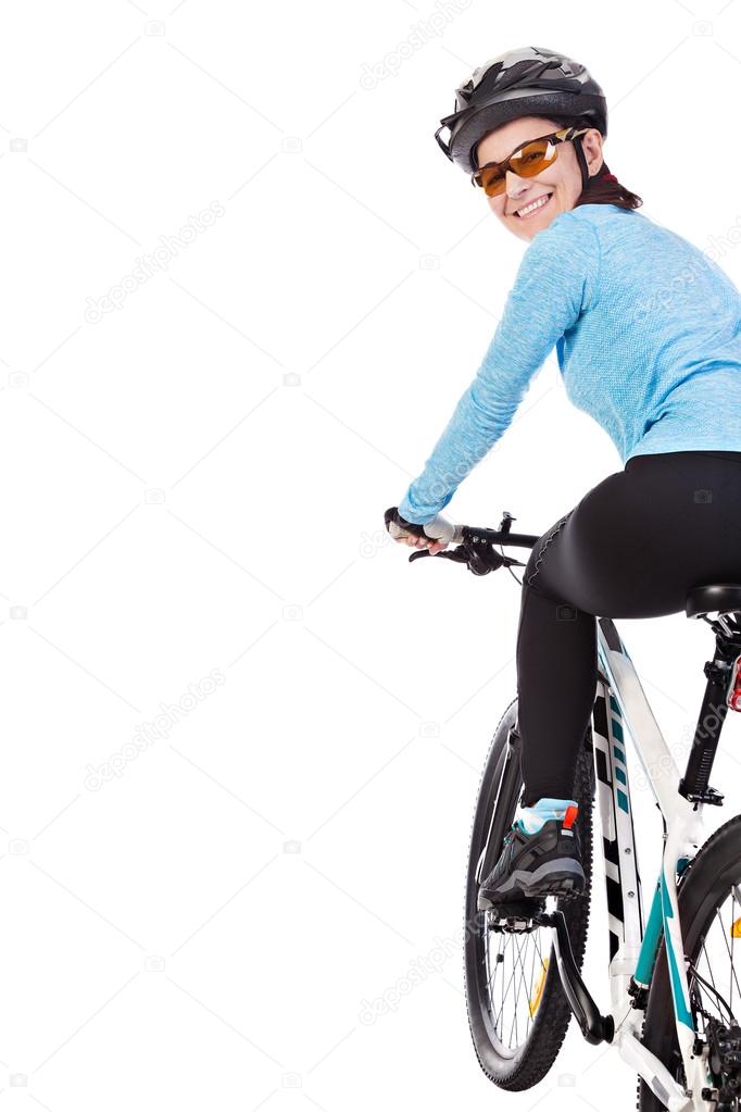Adult woman cyclist riding a bicycle looks back and smiling.