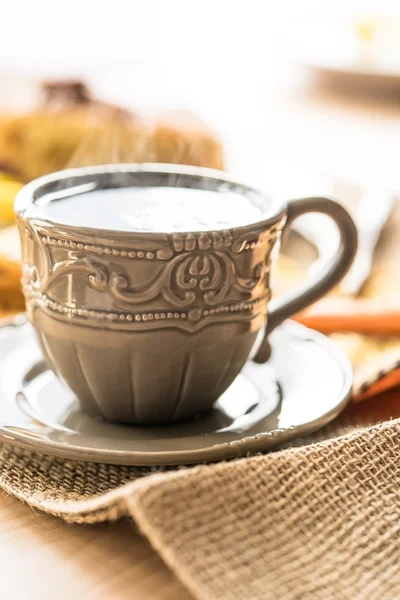 Bir kafe ve pasta arka planda üzerinde dumanı tüten kahve/çay