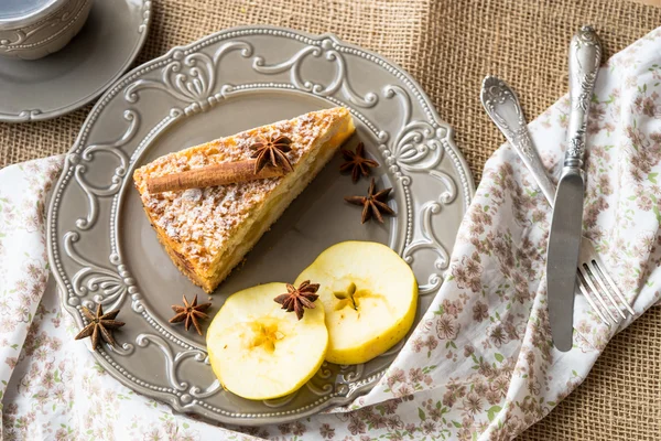 Apfelkuchen mit Zimtstange und Sternanis auf rustikalem Teller mit Apfelscheiben — Stockfoto