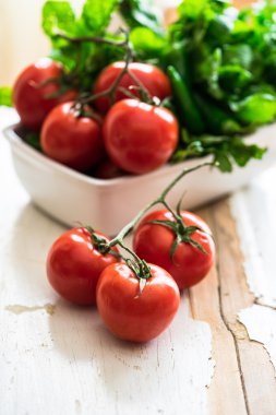 Domates'in ve eski püskü ahşap arka plan üzerinde yapraklı yeşil