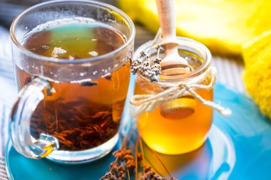 Fincan siyah çay ve kavanoz bal mavi plaka ve örme atkı