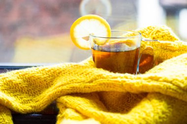 Siyah çay limon sarı süveterin içinde sarılı bir pencere üzerinde