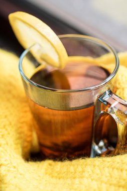 Siyah çay limon sarı süveterin içinde sarılı bir pencere üzerinde