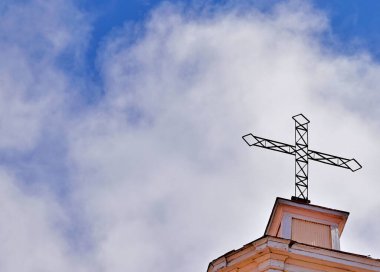 Beyaz bulutlu mavi gökyüzüne doğru yükselen bir haç.