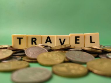 Görüntü TRAVEL kelimesinin para yığınına yerleştirildiğini gösteriyor. Bu seyahat için para biriktirme kavramının görsel bir temsili..