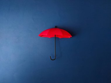 Resim mavi arkaplanda kırmızı bir şemsiye gösterir.