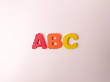 Resim renkli alfabe harflerini gösteriyor, muhtemelen beyaz arka planda tahta harfler..