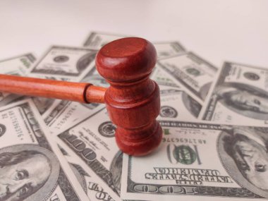 Görüntü, dağınık 100 dolarlık banknotların üzerinde duran ahşap bir tokmağı gösteriyor..