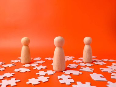 Resim tahta çivili insan figürlerini ve yapboz parçalarını gösteriyor.