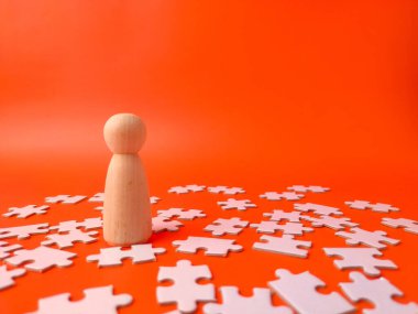 Tahta tahta bebek turuncu arka planda beyaz yapboz parçaları ile çevrili..