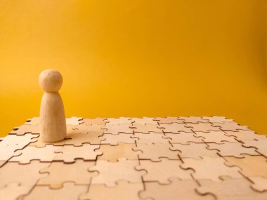 Birbirine kenetlenmiş tahta yapboz parçalarının yüzeyinde duran tahta bir tahta bebek..