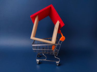 Minyatür ahşap ev modeli ve küçük bir alışveriş arabası..