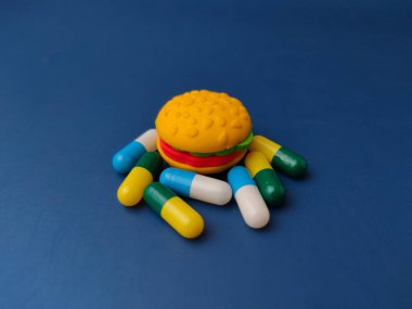 Hamburgerin etrafında çeşitli kombinasyonlarda büyük, renkli kapsüller var..