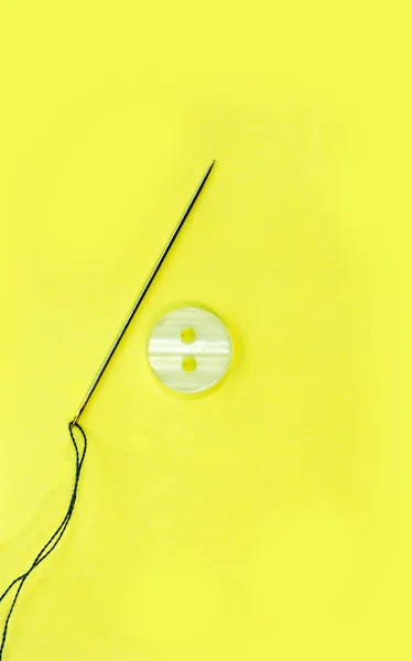 Dikiş iğnesi ve sarı arka plan iş parçacığında.