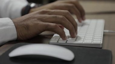 Erkek eller evdeki masada bilgisayar klavyesiyle yazarken, fare ve klavye arasında odak değişimi.