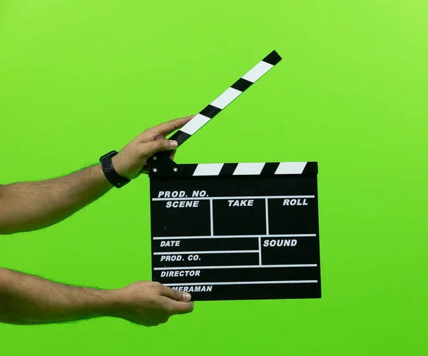 Men\'s hand holding camera slate for the filming isolated on green background. clapperboard in chroma