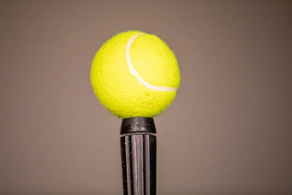 Siyah bir çubukta sabitlenmiş zarif bir yeşil tenis topu. Tenis topu tek çubukta dengeleniyor