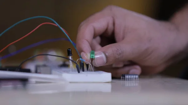 Breadboard 'a bağlanan elektronik bileşenler, bir el dolusu teknisyen ışığı elinde tutuyor