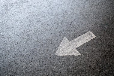 Beyaz ok işareti siyah asfalt üzerinde