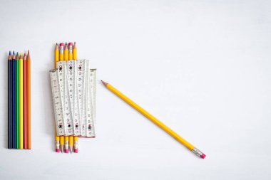 Tahta bir metre beyaz bir arkaplanda bir demet silgi kalemle dinleniyor, metin için yeterli boş alan var.