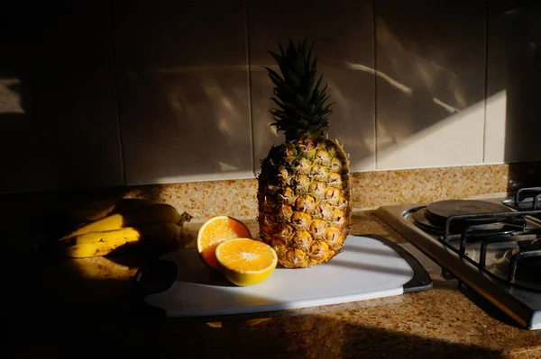 Bir ananas ve mutfakta kesme tahtasındaki diğer meyveler.