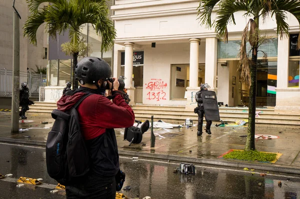 MEDELLN, COLOMBIA - 28 Nisan 2021: Kolombiya 'da ulusal grev için düzenlenen gösterilerde polisin fotoğraflarını çeken gazeteci