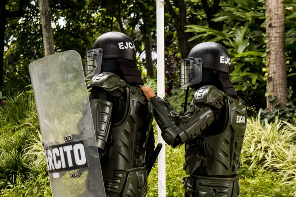 MEDELLN, COLOMBIA - MAYIS 01, 2021: Medellin sokaklarındaki gösterilerde ordunun iki üyesi. Koruyucu giysilerini giyiyorlar.