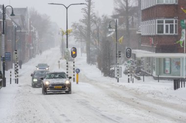 Boskoop, Hollanda, 7 Şubat 2021: Boskoop 'un karlı merkezinden arabalar geçiyor