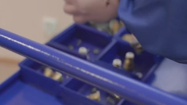 La persona distribuye los componentes de la pieza desmontada en diferentes contenedores — Vídeo de stock