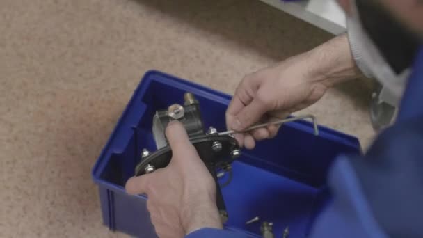 Mennesket demonterer produksjonsdelen på komponentene, skrur av skruene – stockvideo