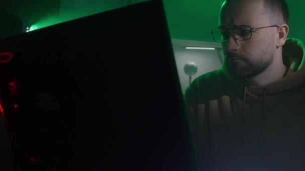 Ein kaukasischer Mann mit Brille arbeitet am Computer, gibt Code ein, tippt sehr schnell auf die Tastatur, überprüft die Informationen, kodiert, studiert, programmiert — Stockvideo
