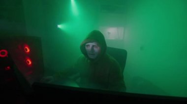 Beyaz maskeli anonim kişi bilgisayarda çalışıyor, kodları giriyor, klavyede çok hızlı yazıyor, bilgiyi kontrol ediyor, kodlama, çalışma, programlama, hackleme