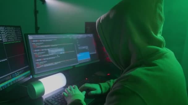 Personne anonyme dans un masque blanc travaille sur l'ordinateur, code d'entrée, types très rapide sur le clavier, vérifie les informations, codage, étude, programmation, piratage — Video