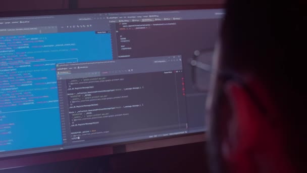 Egy fehér férfi szemüvegben dolgozik a számítógépen, beírja a kódot, nagyon gyorsan gépel a billentyűzeten, ellenőrzi az információt, kódol, tanul, programoz. — Stock videók