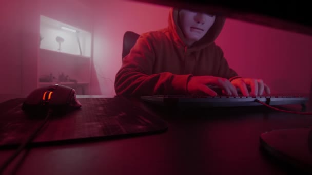 Ανώνυμο άτομο με λευκή μάσκα εργάζεται στον υπολογιστή, εισάγει κώδικα, πληκτρολογεί πολύ γρήγορα στο πληκτρολόγιο, κάνει κλικ στο ποντίκι, ελέγχει τις πληροφορίες, κωδικοποίηση, μελέτη, προγραμματισμός, hacking, gaming — Αρχείο Βίντεο