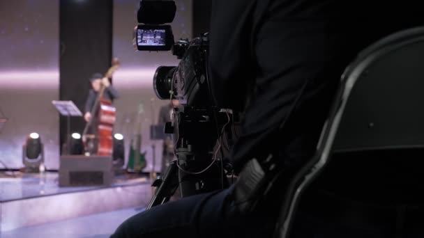 Videógrafo dispara en una cámara profesional un evento musical, músicos, calentamiento, rendimiento — Vídeos de Stock