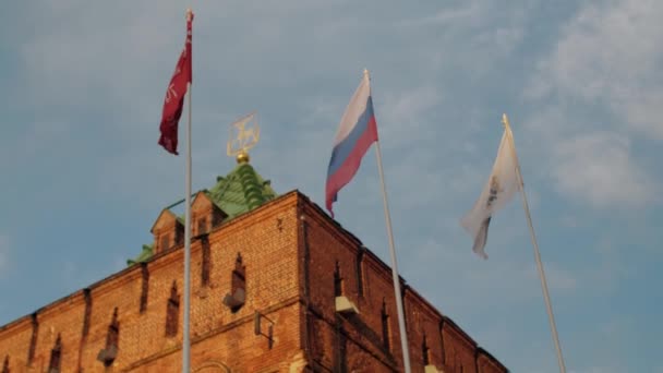 Acenando bandeiras da Rússia e do governo no vento no fundo da torre de Dmitriev do Nizhny Novgorod Kremlin na Rússia, céu azul com nuvens, verão quente — Vídeo de Stock