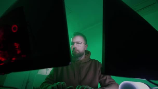 A caucasian man in glasses works on the computer, inputs code, types very fast on the keyboard, checks the information, coding, studying, programming — Stock Video