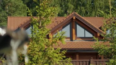View of the house in the cottage village, surrounded by trees, Close up on the splashing water falling from the working fountain in the countryside in summer, park and recreation area on a hot day,