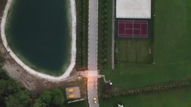 A view from above at the cottage village recreation areas, road, lake, sports grounds: tennis, volleyball, basketball, football and a workout area in the countryside